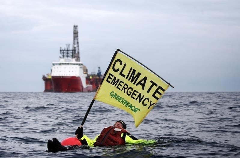 Greenpeace swimmer in front of BP rig