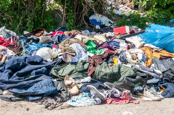 Pile of old clothes and shoes dumped on the grass as rubbish