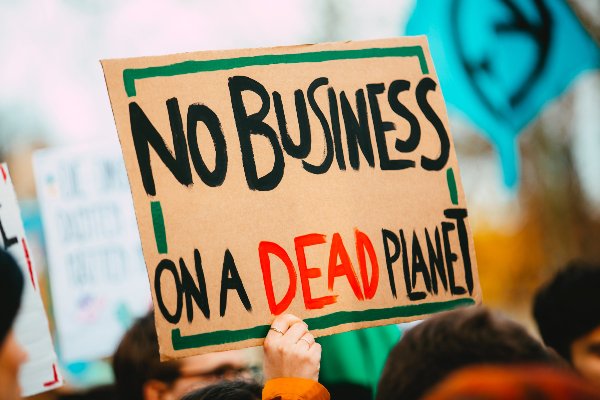 campaigner holding sign that reads 'No business on a dead planet'