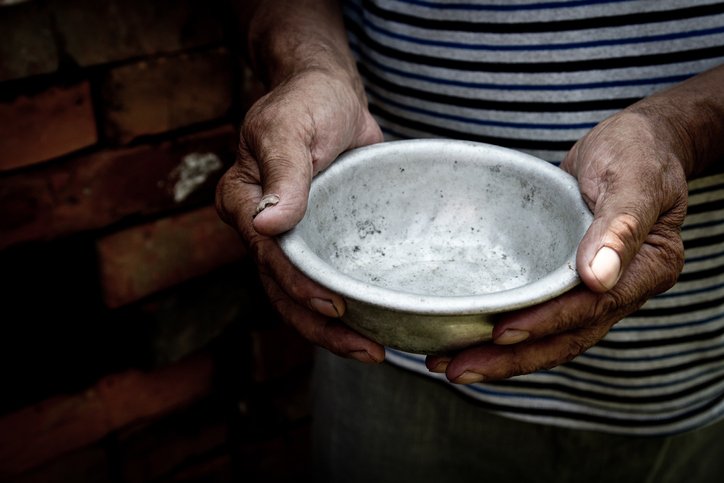 An old man's hands hold an empty bowl