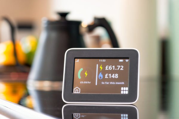 Close-up of the screen of a smart meter display in a kitchen, showing the monthly cost of electricity and gas so far.