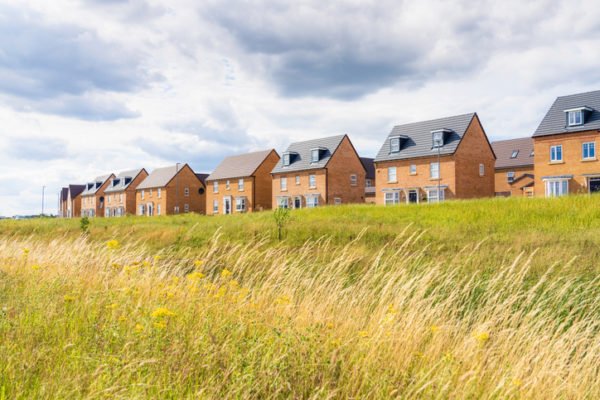 A view across meadow grass to a new build housing estate near Milton Keynes, England