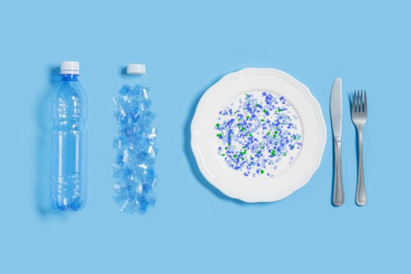 White plate full of microplastics on blue background