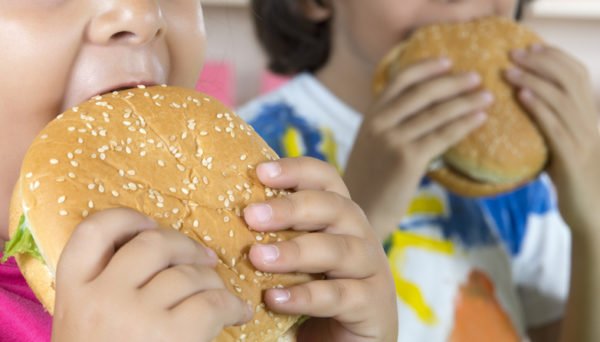 Young boy and girl eating hamburgers