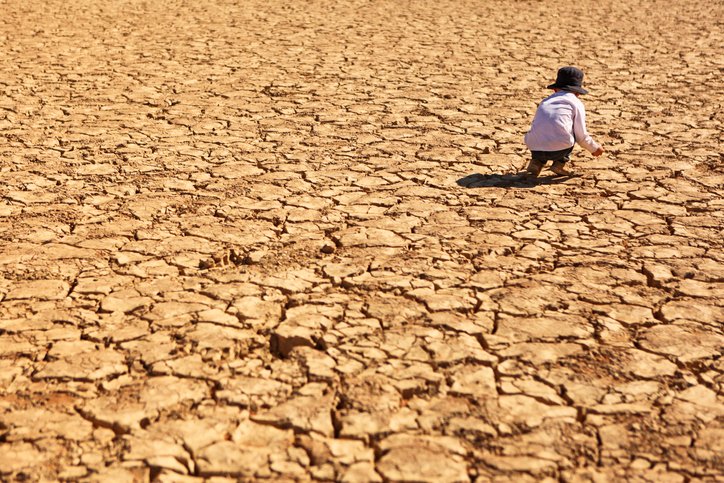 Child playing on dry brown cracked land in the heat of the desert at Deadvlei in Namib-Naukluft National Park in Namibia, Africa