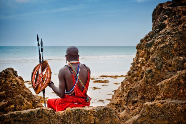 African man of the Maasai tribe in Kenya sits on the ocean and looks into the distance