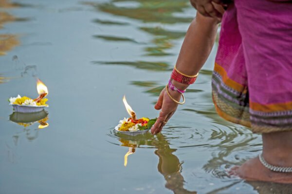 Indian woman puts candle on plate in water to pray the good luck in the puja ritual, Ganges, India