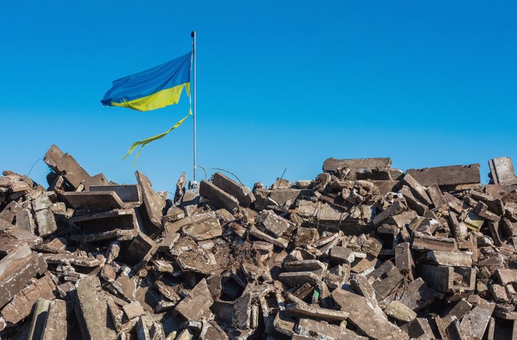 Destroyed Ukrainian building and damaged flag in the wind