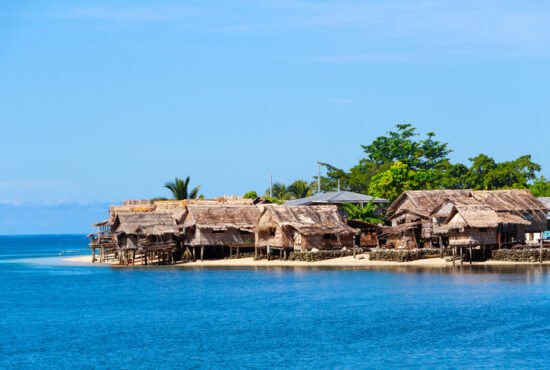Photo of traditional thatched houses on a beautiful beach in Auki, the provincial capital of Malaita Province, Solomon Islands