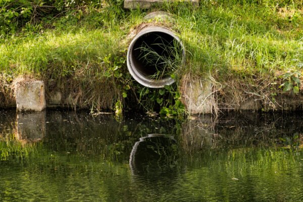 Sewer pipe leading into water in the countryside