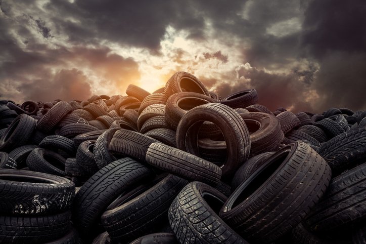Pile of old used car tyres under a sky full of dark clouds