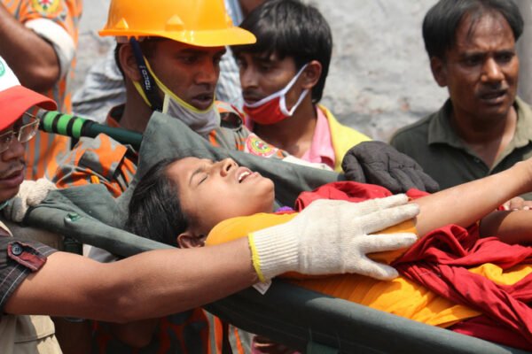 Rescuers bring out an injured worker from the rubble of the collapsed Rana Plaza factory building