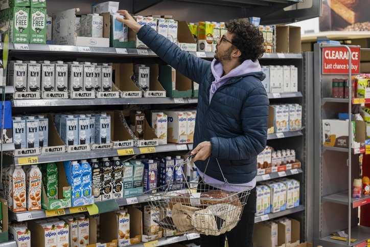 Man choosing a vegan milk from a supermarket shelf