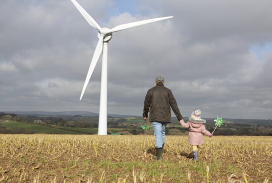 Father and daughter walk to wind turbine