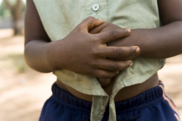 A little African girl with hands over her stomach symbolising hunger