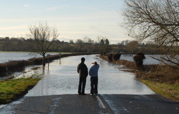 Two people looking at a road flooded by the River Avon in Worcestershire