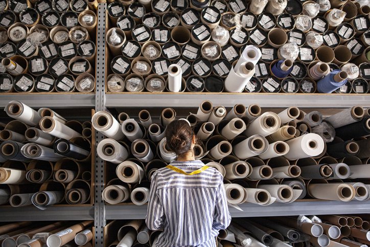 Textile designer standing next to fabric rolls inside sustainable workshop