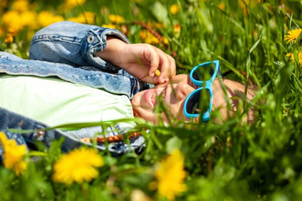 Young girl in sunglasses lies in a summer meadow