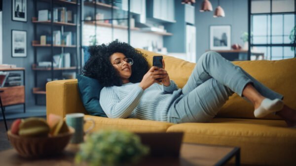 Happy female using smartphone in cosy living room at home