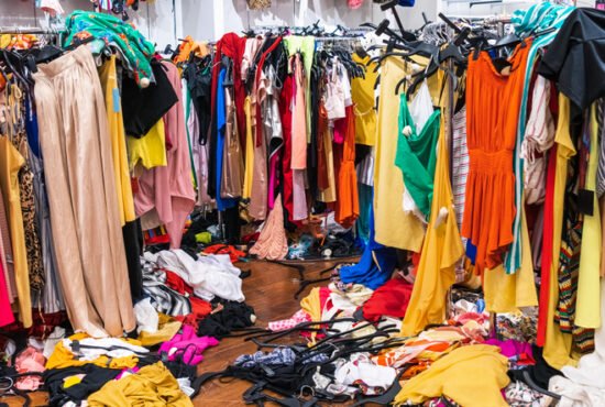 Colourful garments on racks and on the floor; fast fashion