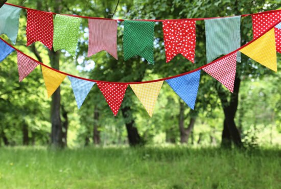 Close-up of bunting flags hanging among trees in a summer garden
