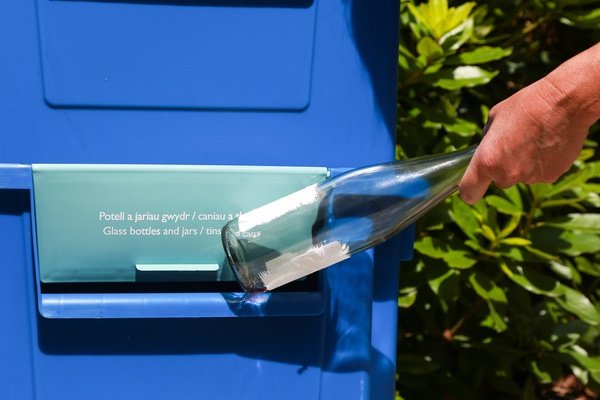 Recycling a glass bottle at council box in Wales