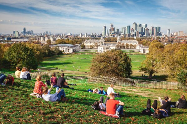Young people relax in Greenwich Park on a summer afternoon and await the sunset