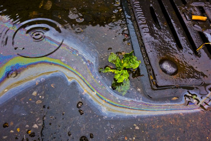 Oil in water running down a drain in the road