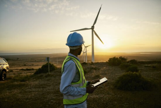 Engineer man, tablet and wind turbine on sunset farm for clean energy, power and electricity