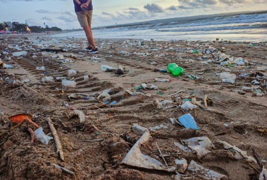 Man walking on a Bali beach littered with plastic