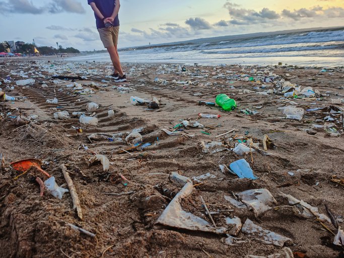 Man walking on a Bali beach littered with plastic