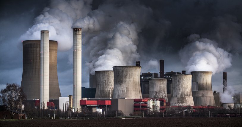 Chimneys and cooling towers from a coal-fired power station releasing smoke and steam into the atmosphere. The power plant is also releasing CO2 which contributes to global warming and climate change.