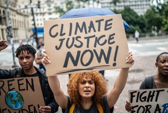 Mid adult woman holding a 'Climate Justice' sign during a demonstration in the street