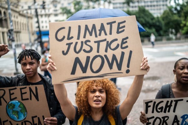 Mid adult woman holding a 'Climate Justice' sign during a demonstration in the street