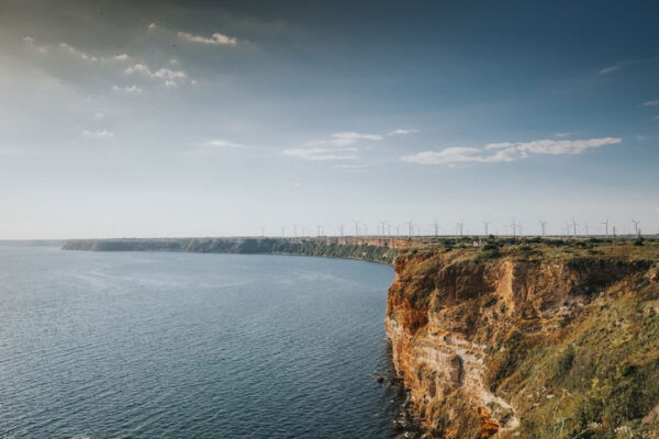 Sunset landscape by the sea with wind turbines