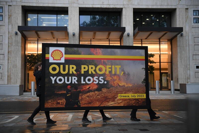 Greenpeace UK protesters erect a giant spoof billboard outside Shell’s HQ accusing them of fueling climate change and therefore complicity in last week’s devastating wildfires in Southern Europe as the company announced billions in profits from the last three months. The billboard, which features an image of a Greek firefighter battling to contain a wildfire near Athens last week, is emblazoned with Shell’s logo and features the slogan “Our profit, your loss”, drawing attention to the oil and gas industry’s responsibility for the climate crisis- fueled extreme weather that people are now experiencing across the world at unprecedented rates