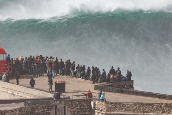 Giant wave crashing into cliff and lighthouse in Nazare, Portugal after major Atantic storm