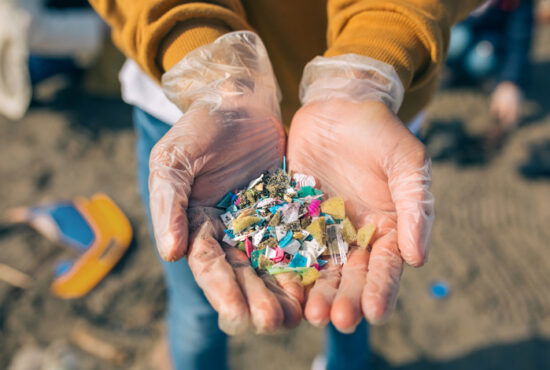 Detail of hands showing microplastics on the beach