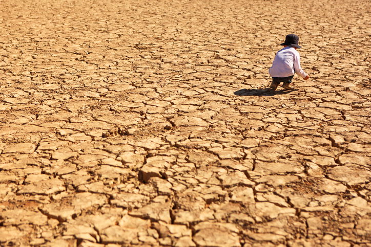 Child playing on dry, brown, cracked land in the heat of the desert at Deadvlei in Namib-Naukluft National Park in Namibia, Africa