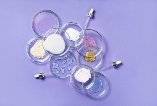 Cosmetic products, scrub, face serum and gel in many petri dishes on a pink background