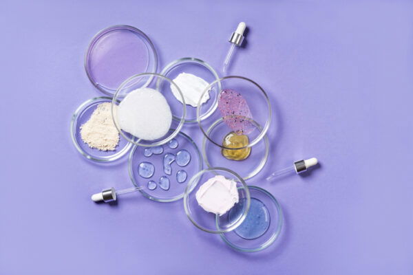 Cosmetic products, scrub, face serum and gel in many petri dishes on a pink background