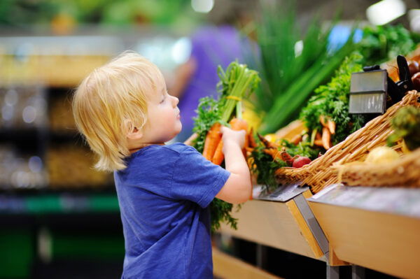 Toddler boy in a supermarket choosing fresh organic carrots