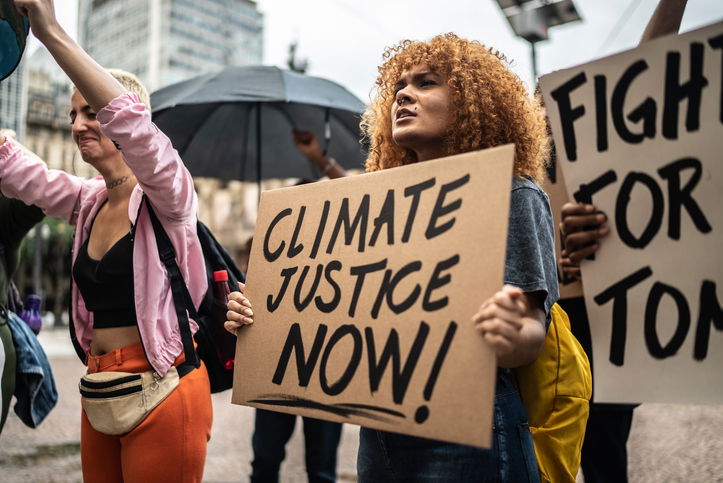 Protesters holding climate justice signs during a demonstration in the street