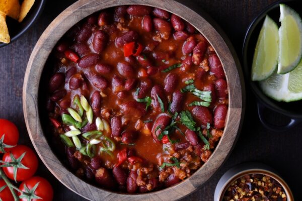 Pot of delicious beans in a chilli, with garnish of lime and cherry tomatoes